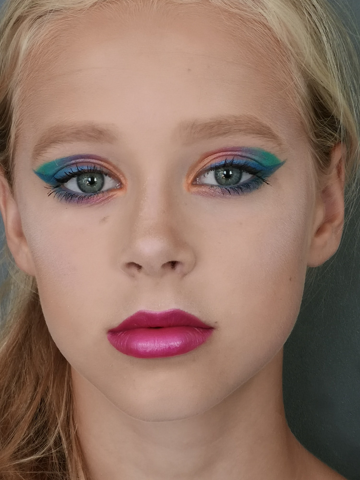 Girl face with pink lipstick and rainbow colored eye makeup